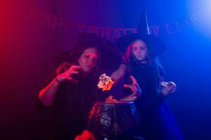 Funny child girl and woman in witches costumes for Halloween making magic. photo
