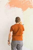 Young man using spatula and plastering of wall with white fresh finishing putty. Closeup. Repair work of home. photo