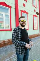 Portrait of happy travel man with suitcase standing near the building in city. photo