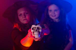 Two halloween witches making magic with scull in halloween night. Magic, holidays and mystic concept. photo
