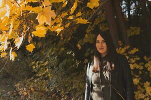 asiático morena mujer en pie en un parque en otoño. otoño y temporada concepto. foto