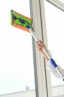 Washing window with special mop and cleaning services - housework and housewife concept photo