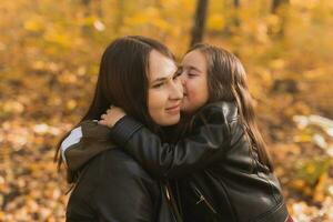 Little girl playing with mother in the autumn park photo