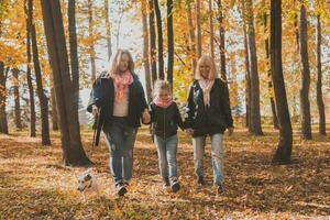 Grandmother and mother with granddaughter walks together in autumn park and having fun. Generation, leisure and family concept. photo