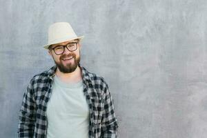 Handsome guy tourist looking happy wearing straw hat for travelling, standing against concrete wall background with copy space photo