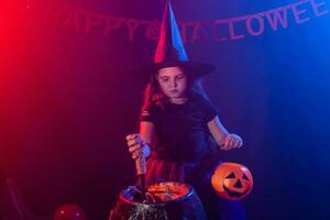 Little witch child cooking potion in the cauldron on Halloween. photo