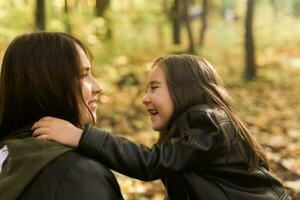 Little girl playing with mother in the autumn park photo