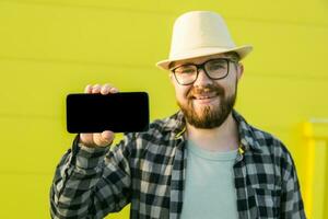 Hot offering. Happy guy holds cellphone with black copy space and smiling. Human emotions facial and place for advertising and text photo