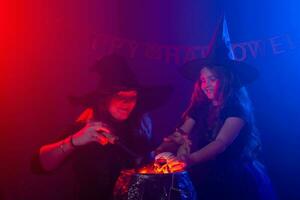 Funny child girl and woman in witches costumes for Halloween. photo