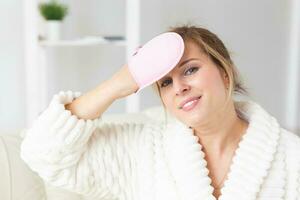 Excited joyful young woman wrapped head in towel holding dry brush shower sponge and doing spa procedure photo