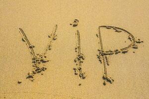 written word VIP on sand of beach in sunny day photo