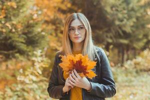 Girl holds fallen leaves in autumn park. Seasonal concept. photo