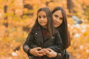 pequeño niña jugando con madre en el otoño parque foto