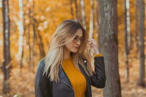 Portrait of young urban stylish young woman walking in fall park. Autumn season. photo