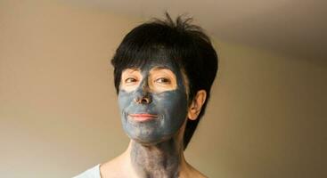 Beautiful woman with facial mask. Cosmetology, spa, skin care and people concept. photo