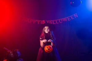 Funny child girl in witch costume for Halloween with pumpkin Jack. photo