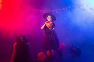 Funny child girl in witch costume for Halloween with pumpkin Jack. photo