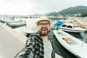 viajero hombre tomando selfie de lujo yates marina durante soleado día - viaje y verano concepto foto