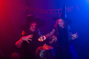 Two halloween witches making a potion and conjure in halloween night. Magic, holidays and mystic concept. photo