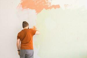 Young man using spatula and plastering of wall with white fresh finishing putty. Closeup. Repair work of home. Empty place for text. Side view. photo