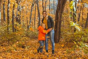Mother hugging her child during walk in autumn park. Fall season and single parent concept. photo