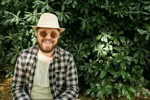 riendo atractivo hombre vistiendo sombrero terminado verde árbol antecedentes con Copiar espacio - emoción y vacaciones viaje Días festivos concepto foto