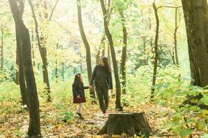 Mother and her little daughter in autumn park in fall season. photo