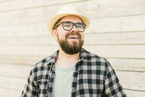 Laughing attractive man wearing hat over wooden background - emotion and vacation travel holidays concept photo