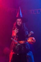 Little witch child cooking potion in the cauldron on Halloween. photo