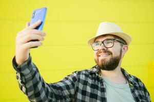 Man telling something at the camera while traveling at new city, yellow street wall background. Blogger and vlog concept photo