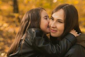 Mother and daughter spend time together in autumn yellow park. Season and single parent concept. photo