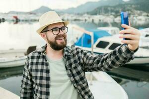 Traveller man taking selfie of luxury yachts marine during sunny day - travel and summer concept photo