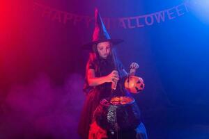 Little witch child cooking potion in the cauldron on Halloween. photo