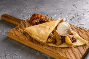 Crepes stuffed with fruit and nuts. Served with ice cream ball. Thin pancakes, sweet dessert photo