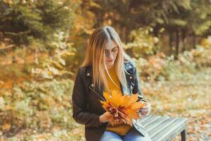 joven mujer participación otoño hojas en otoño parque. estacional, estilo de vida y ocio concepto. foto