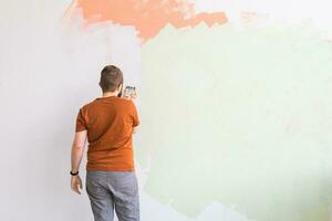 Young man using spatula and plastering of wall with white fresh finishing putty. Closeup. Repair work of home. Empty place for text. Side view. photo