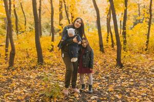 Portrait asian mother playing with leaves with her son and daughter during walk in park photo