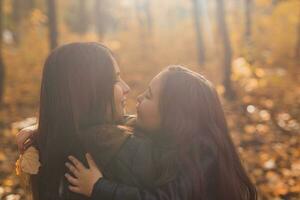 Mother and daughter spend time together in autumn yellow park. Season and single parent concept. photo