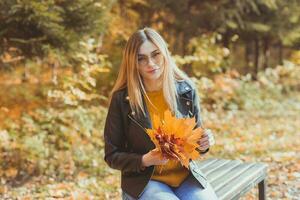 niña sostiene caído hojas en otoño parque. estacional concepto. foto