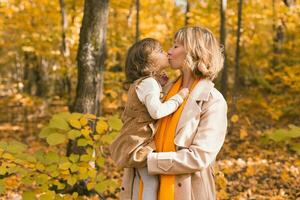 joven madre con su pequeño hija en un otoño parque. otoño estación, paternidad y niños concepto. foto