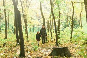 Young woman and her child girl walking through park. Single parent and motherhood concept. photo