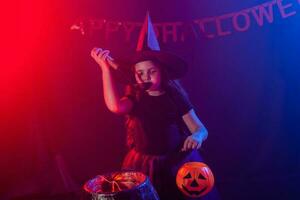 Little witch child cooking potion in the cauldron on Halloween. photo