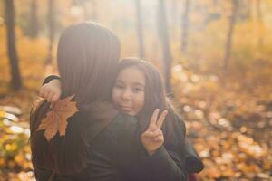 Mother and daughter spend time together in autumn yellow park. Season and single parent concept. photo