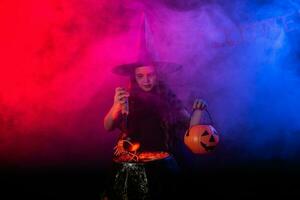 Little witch child cooking potion in the cauldron on Halloween. photo