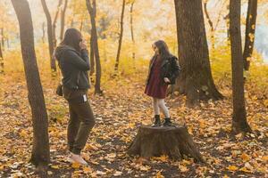 madre tomando imagen su carismático hija en retro cámara en otoño parque. aficiones y ocio concepto. foto