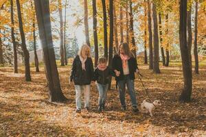Grandmother and mother with granddaughter walks together in autumn park and having fun. Generation, leisure and family concept. photo