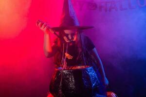 Little witch child cooking potion in the cauldron on Halloween. photo