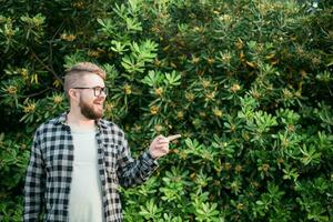 cerca arriba retrato hermoso joven hombre punto terminado verde arbusto fuera de Copiar espacio y sitio para publicidad. foto