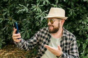 Bearded man doing video call on smartphone outdoor - video connection and technologies concept photo