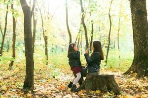 Little girl playing with mother in the autumn park photo